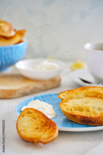 Crushing slices of baguette on a plate with a cup of tea.