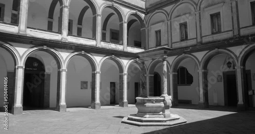 Naples, Italy. Black and white shot of a courtyard in Certosa di San Martino, a monumental charterhouse at daytime. Overview of the large cloister with numerable windows and doors. photo