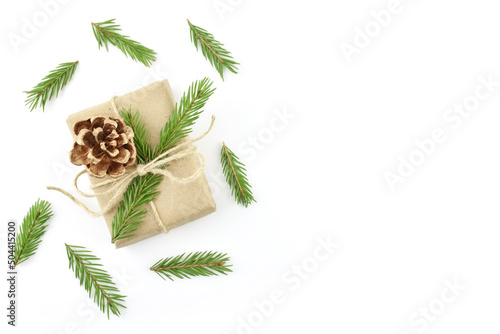 A Christmas gift in craft paper, decorated with a fir cone, cinnamon and twigs. New Year's white background with natural color decor. Isolated Christmas paraphernalia
