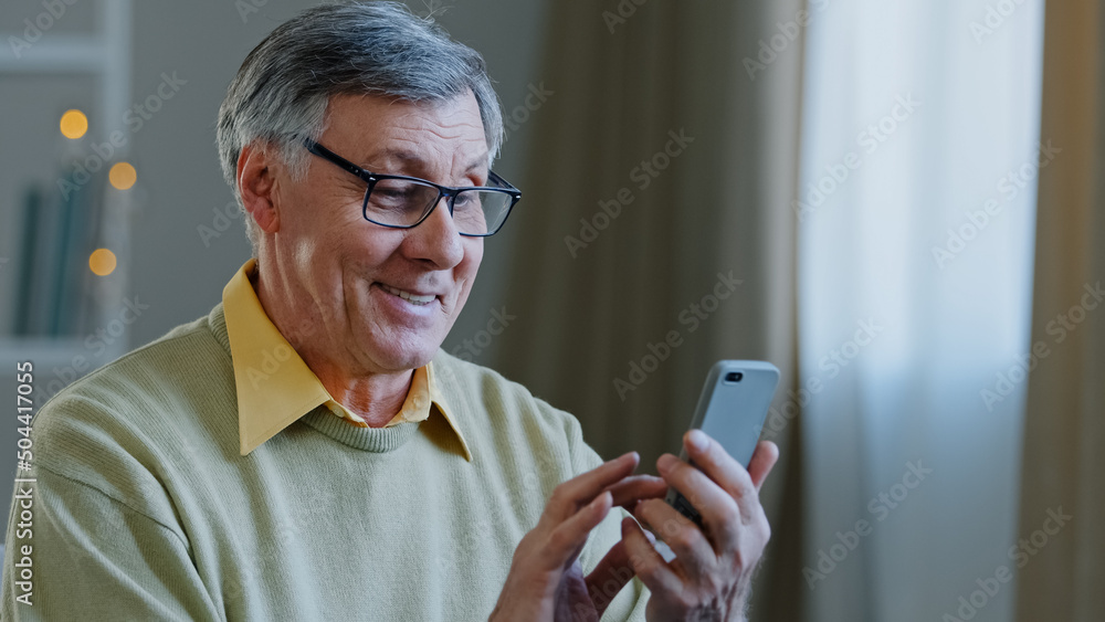 Mature elderly mature 60s caucasian man with phone male grandfather uses  mobile app at home buys medicine online brows on net writes message to  children in smartphone technology and old generation Photos