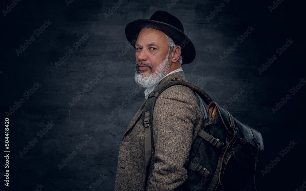 Studio shot of stylish grandfather dressed in beige suit and hat carrying backpack. Studio shot of stylish grandfather dressed in beige suit and hat carrying backpack.