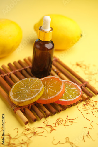 Essential oil bottle and lemon on yellow background 