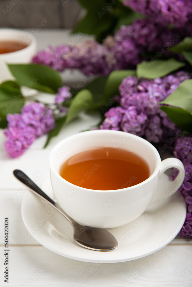 A cup of green tea against the background of a spring bouquet of lilacs on a textured gray background.Romantic composition with books and candles. Spring tea drink. Place to copy. A cup of green tea against the background of a spring bouquet of lilacs on a textured gray background.Romantic composition with books and candles. Spring tea drink. Place to copy.