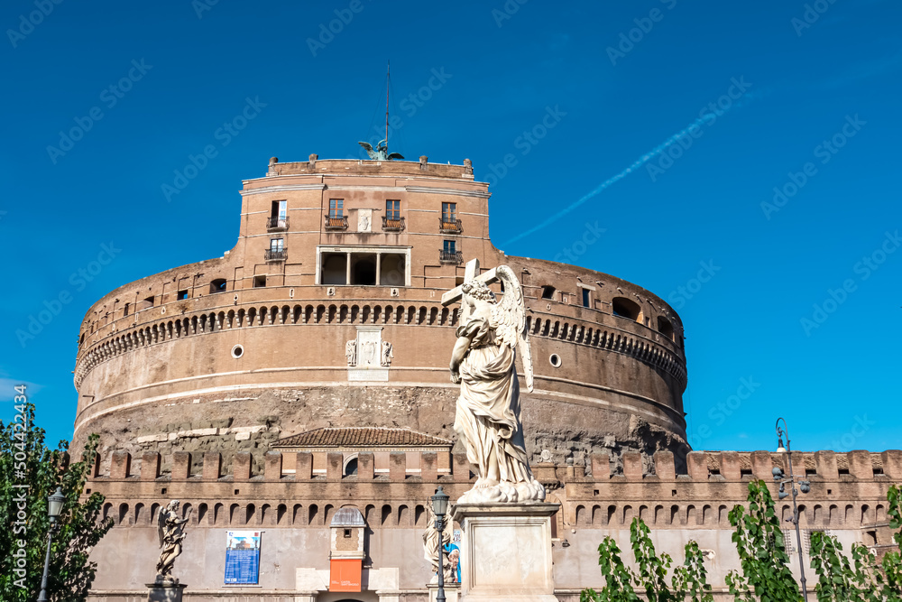 Close up view from the Aurelius bridge on the Mausoleum of Hadrian (Castel Sant Angelo) in Rome, Lazio, Europe, EU. Stone statue of an Angel holding a cross standing below the landmark