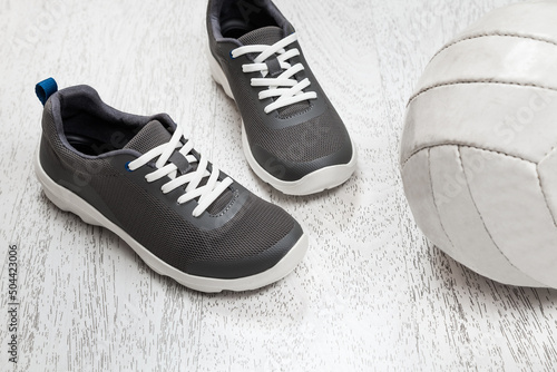 Active healthy living concept: running shoes, ball on white wooden background.