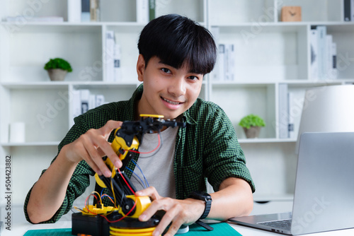 Asian teenager constructing robot arm homework project in house. technology of robotics programing and STEM education concept.