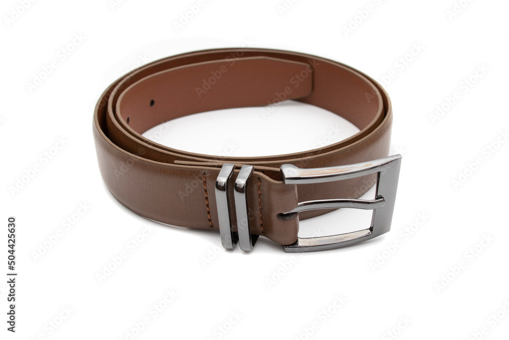 A brown belt with a metal buckle, rolled up. Selective focus. Isolated on white background.