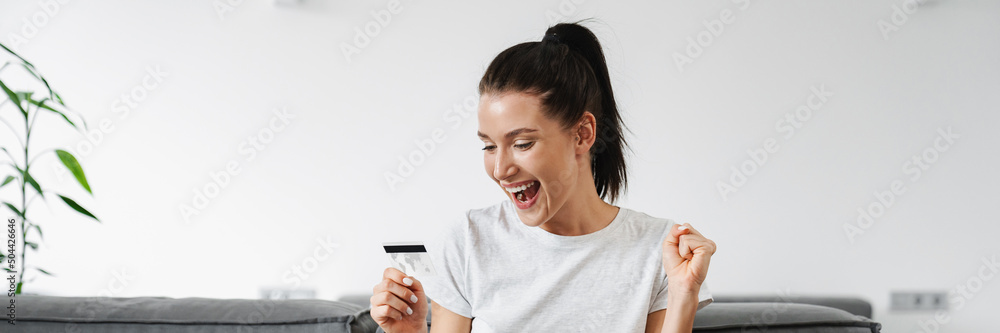 Excited woman making winner gesture while using credit card and laptop Excited woman making winner gesture while using credit card and laptop