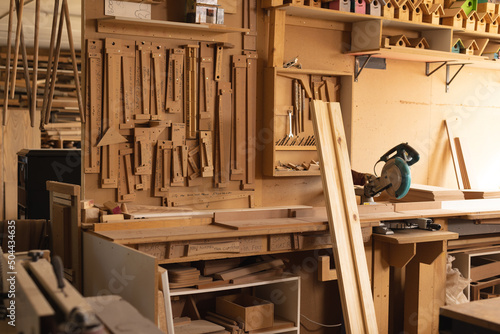 Interior of workshop with planks and various woodworking tools hanging on rack in workshop photo