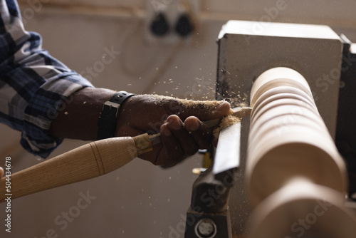 Cropped image of african american mature carpenter shaping and carving wood at workshop