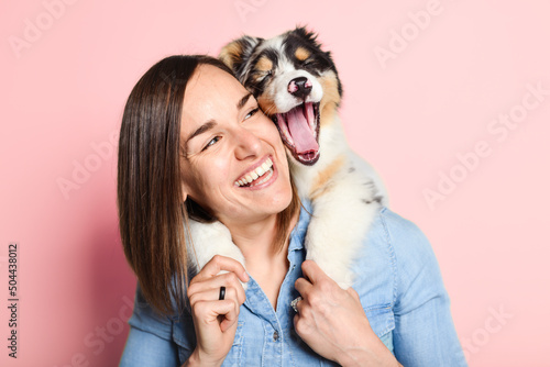 Handsome female with her Australian Berger puppy on studio pink #504438012