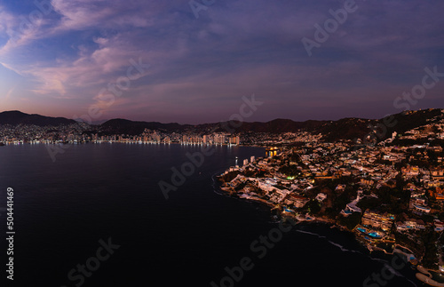 Aerial photo with a drone from the sea in the Las Brisas area of the Bay of Acapulco after sunset at the blue hour with purple tones in the sky