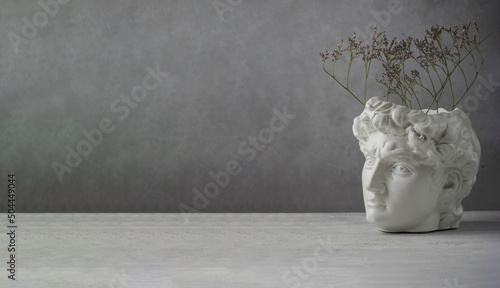White copy plaster statue of the head of David on a gray concrete background. Minimal art poster. Ancient Greek sculpture. copy space. Banner. photo
