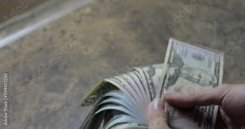 The girl is holding dollars in her hands, bills folded in a fan.