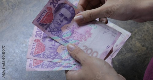 Dollars in female hands on background of wooden table. Woman counting 100 and 50 American dollar banknotes in arms. Lots of one hundred dollar bills. Banknotes on wooden table. Finance, economy, savin