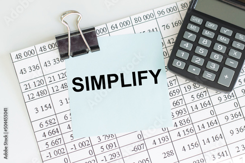 SIMPLIFY text on a blue card clip to a sheet of numbers on a calculator table