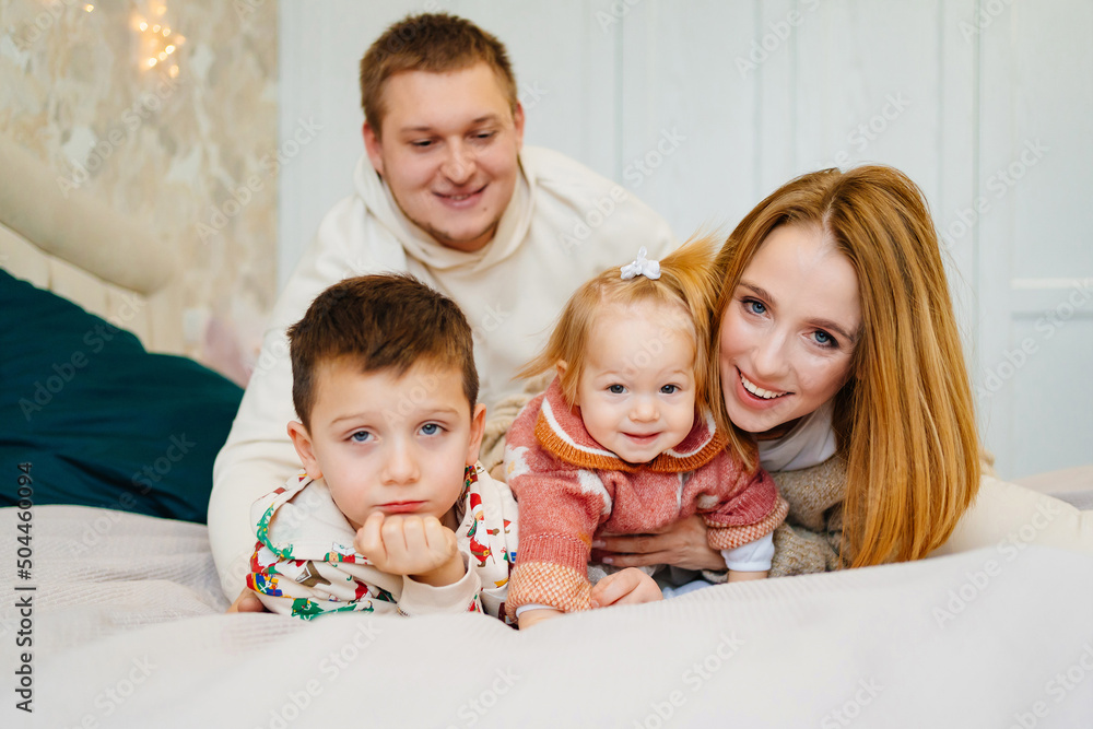 portrait of a happy family with two children lies in a cozy bed in the bedroom. portrait of a happy family with two children lies in a cozy bed in the bedroom.