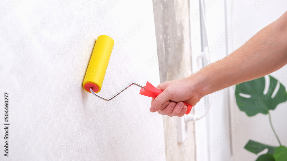 custom made wallpaper toronto digitalA man rolls out a canvas of white wallpaper with a suture yellow roller. Removing air bubbles and glue. Wallpapering. Repair of a room, apartment, house.