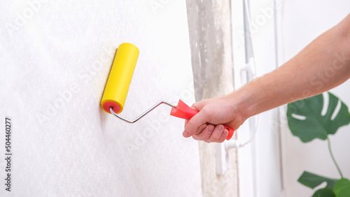 Wallpaper Mural A man rolls out a canvas of white wallpaper with a suture yellow roller. Removing air bubbles and glue. Wallpapering. Repair of a room, apartment, house. Torontodigital.ca
