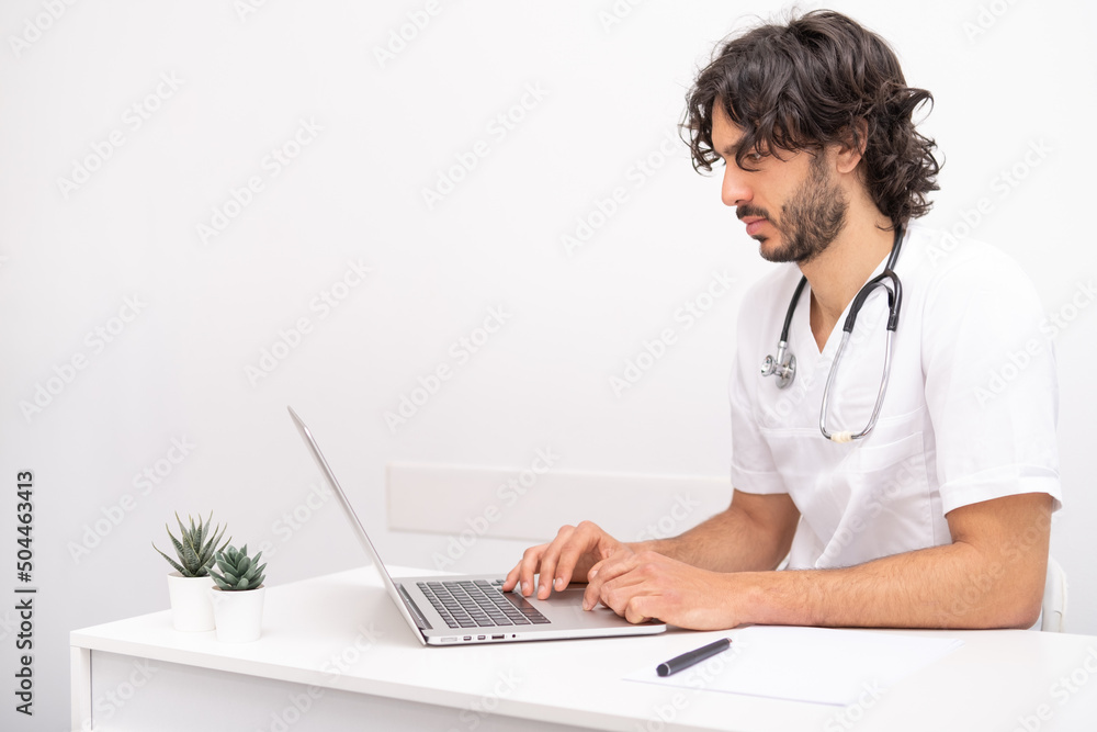 young man doctor with stethoscope using computer laptop talking video conference call with patient at desk in health clinic. Consulting and healthcare concept young man doctor with stethoscope using computer laptop talking video conference call with patient at desk in health clinic. Consulting and healthcare concept