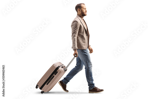 Full length profile shot of a man walking and pulling a suitcase