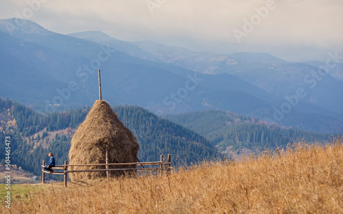 Man sitting on a fence in the middle of the mountains photo