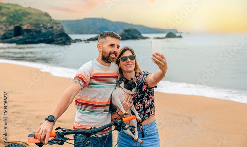 Young couple with their dog taking a selfie on the beach