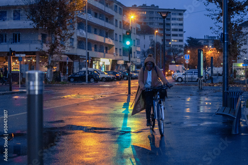 woman riding bike by night, commute by bicycle in snowy cold weather