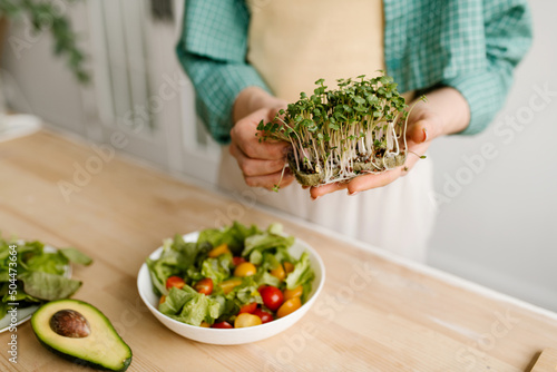Woman Adding Microgreens To Salad photo