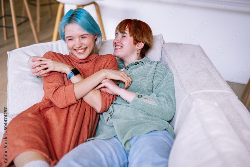 Lesbian couple hugging on sofa Lesbian couple hugging on sofa