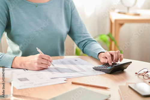 Crop woman counting expenses and reading bills photo