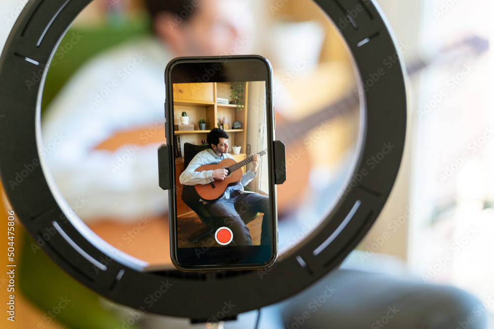 Close-up of phone screen of Man shooting a video playing guitar Close-up of phone screen of Man shooting a video playing guitar