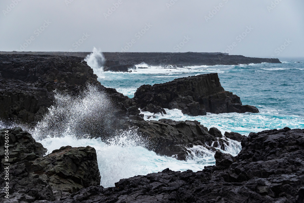 The coastal cliffs near Brimketill rock pool on a stormy day, with huge sea waves crashing against the black basalt rocks, Reykjanes peninsula, Iceland