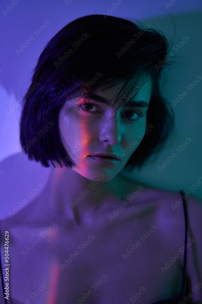 young woman model looking at the camera under colorful lighting young woman model looking at the camera under colorful lighting