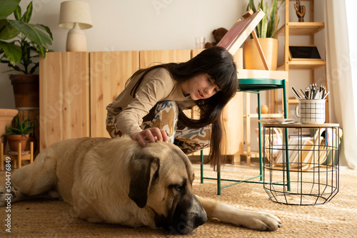 Nice girl caressing her big dog at home photo