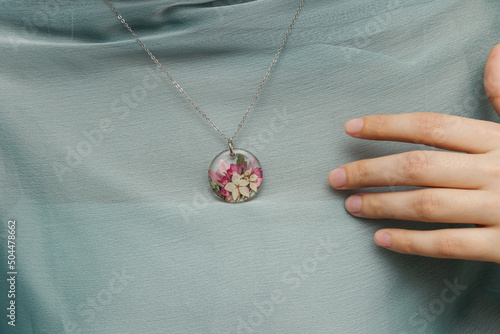 Close up of female hands holding floral epoxy necklace photo