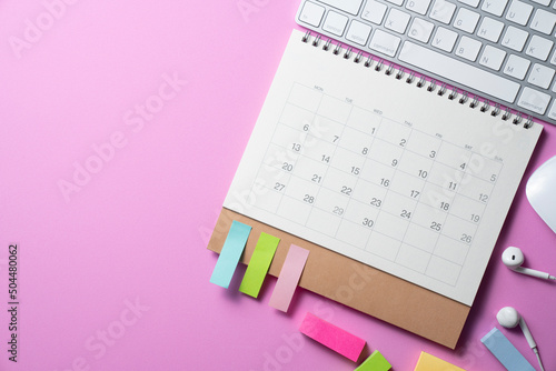 close up of calendar and computer keyboard on the pink table background, planning for business meeting or travel planning concept