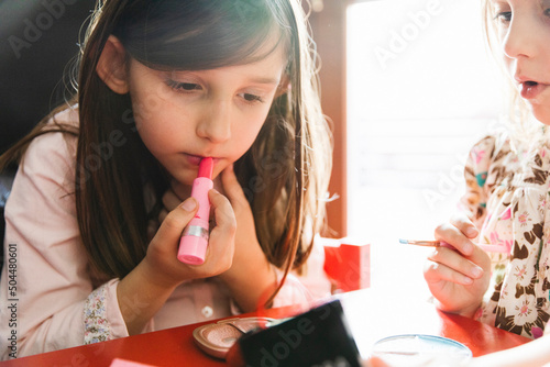 Little girl puts on lipstick photo