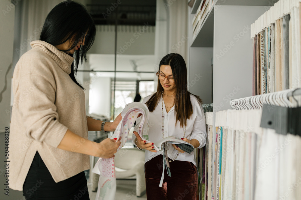 Female Shop Assistant Showing To Her Customer Different Fabrics