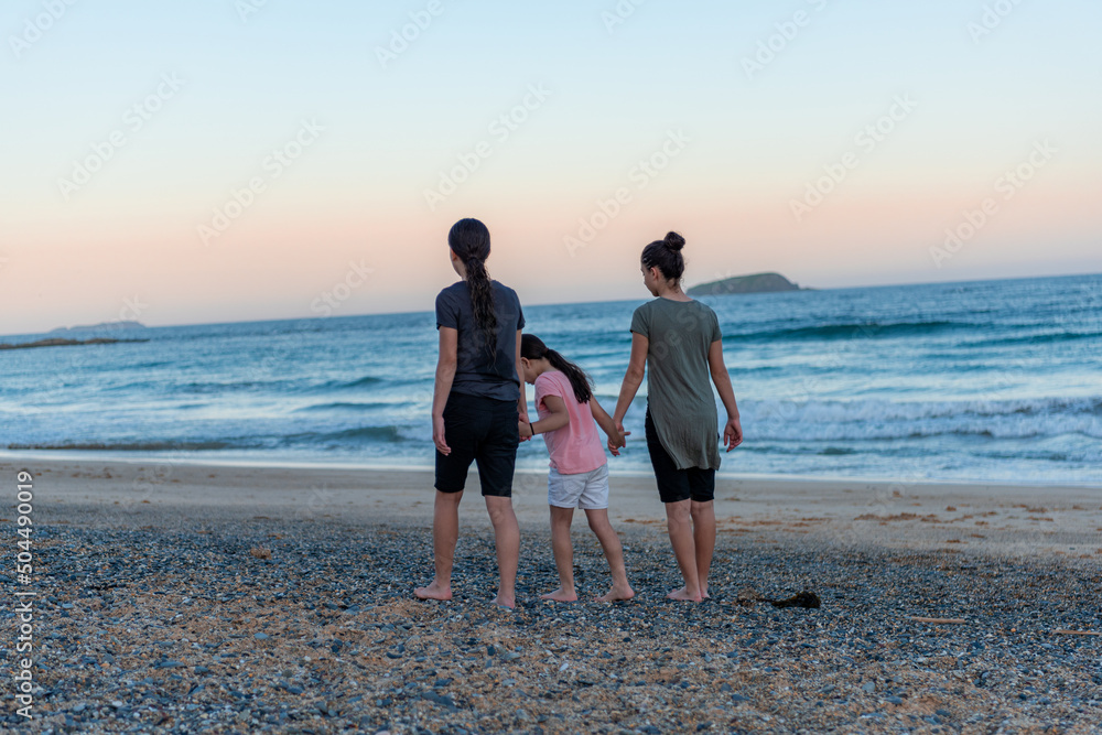 Young girls holding hand and walking together, embracing nature on the beach, sea landscape. 