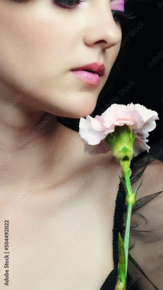 Closeup slow motion vertical video of female with pink carnation flower near face. Closeup slow motion vertical video of female with pink carnation flower near face.