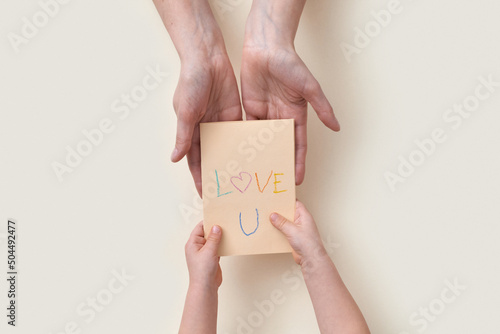 Kid giving greeting card with text Love U to mum photo