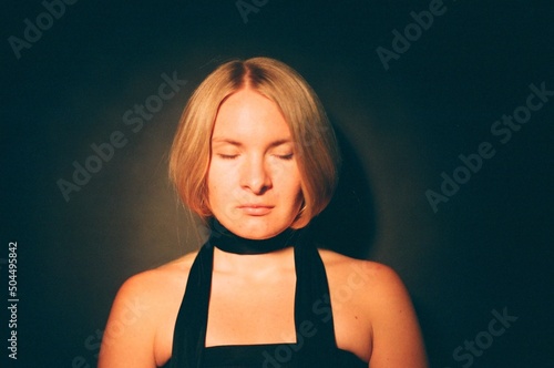 A dreamy woman in a dark studio with closing eyes photo