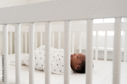A baby laying in a simple crib