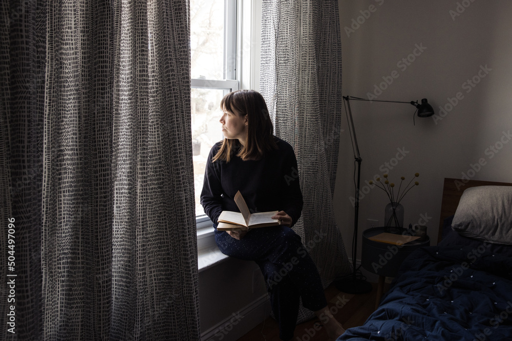 Woman reading book by the window Woman reading book by the window