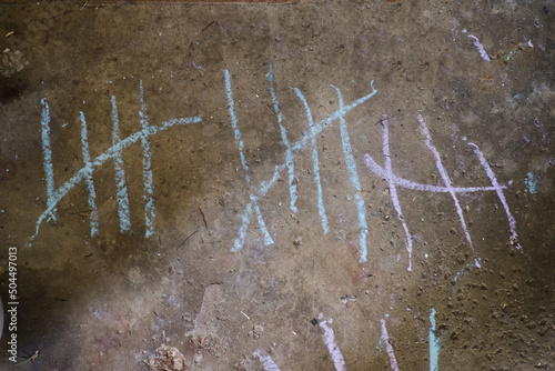 A child's chalk written tally marks on garage floor photo