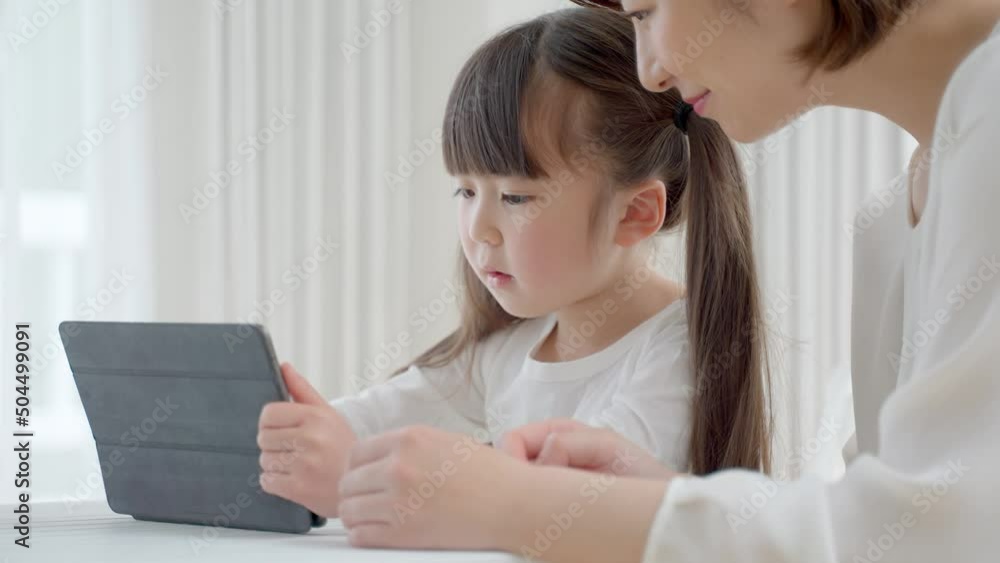 タブレットを使って学習する娘と母 タブレットを使って学習する娘と母