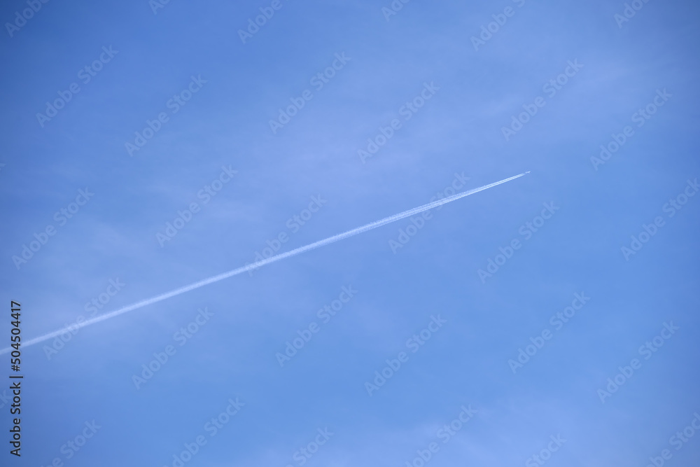 Distant passenger jet plane flying on high altitude on clear blue sky leaving white smoke trace of contrail behind. Air transportation concept Distant passenger jet plane flying on high altitude on clear blue sky leaving white smoke trace of contrail behind. Air transportation concept