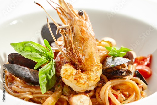 Italian dish - seafood linguine isolated on white background. Pasta with prawn, mussels, octopus, squid in tomatoes marinara sauce. Seafood pasta in Italian restaurant menu. Seafood on white plate