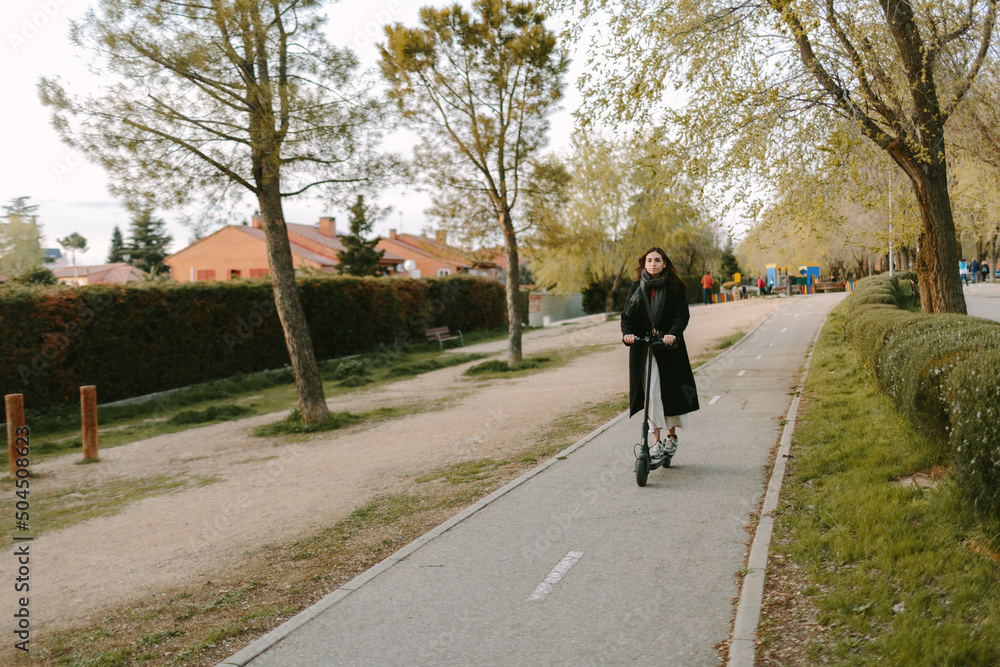 Woman riding an e-scooter in bike lane. Sustainable city concept. Woman riding an e-scooter in bike lane. Sustainable city concept.